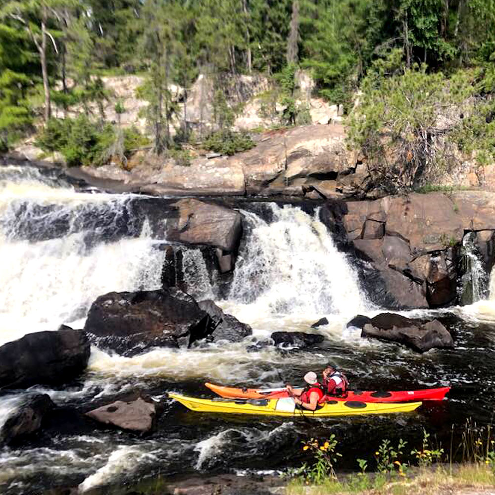 two people in kayaks on a river coming close to rapids