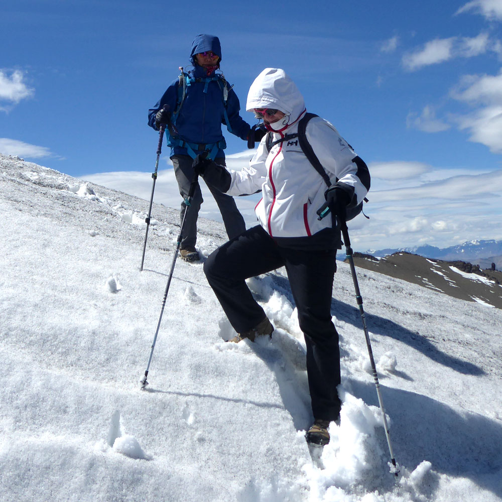 two people going down a snowy hill on snowshoes using poles